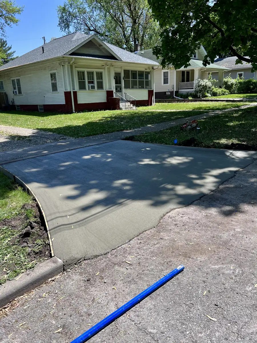 Curved concrete driveway approach meeting the sidewalk in front of a white house