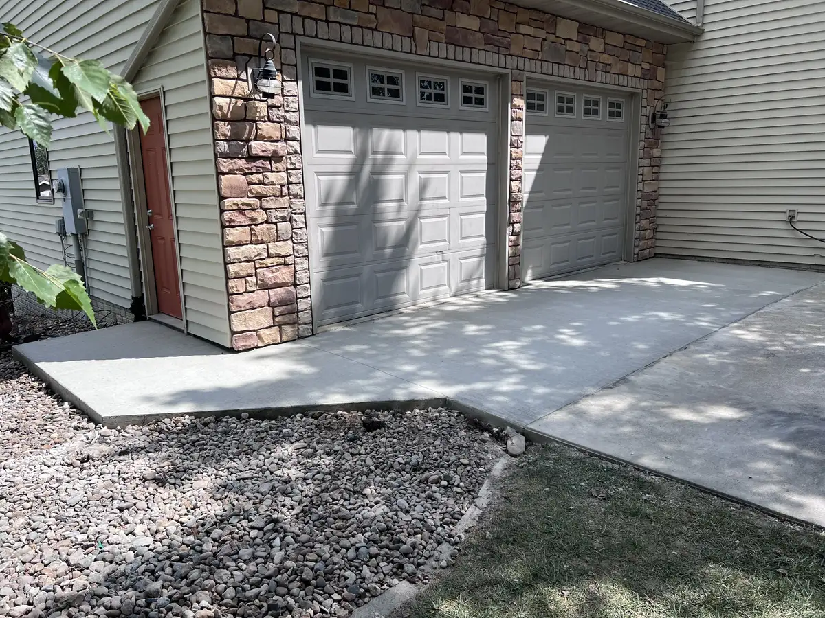 Concrete garage apron and walkway in front of a stone-front garage
