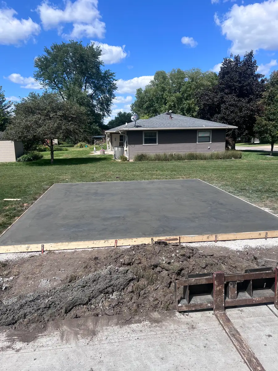 New concrete garage pad poured beside a house, forms still in place