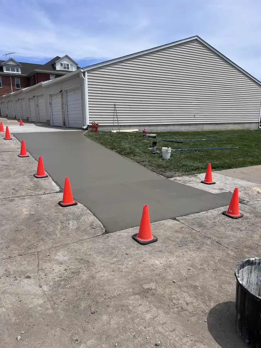 New concrete drive along a row of garages, coned off while it cures