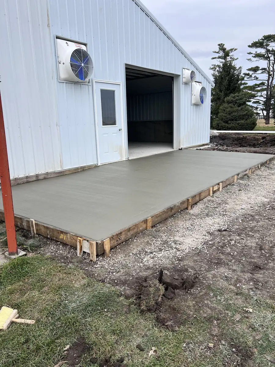 Concrete apron poured in front of a white steel shop door